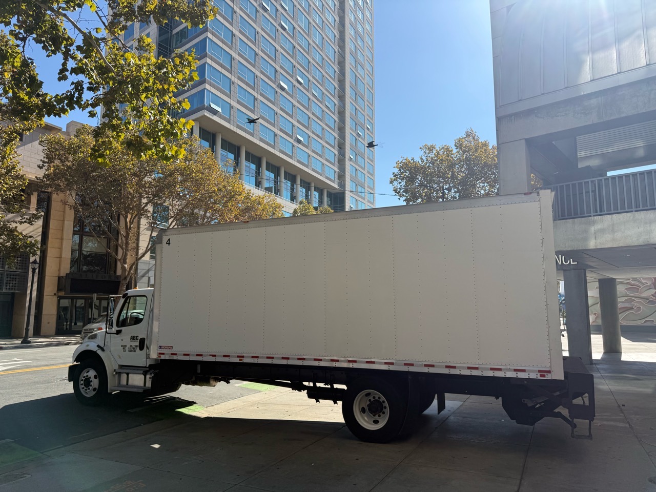Rear three-quarter view of ABC DELIVERED's white box truck with the liftgate platform deployed